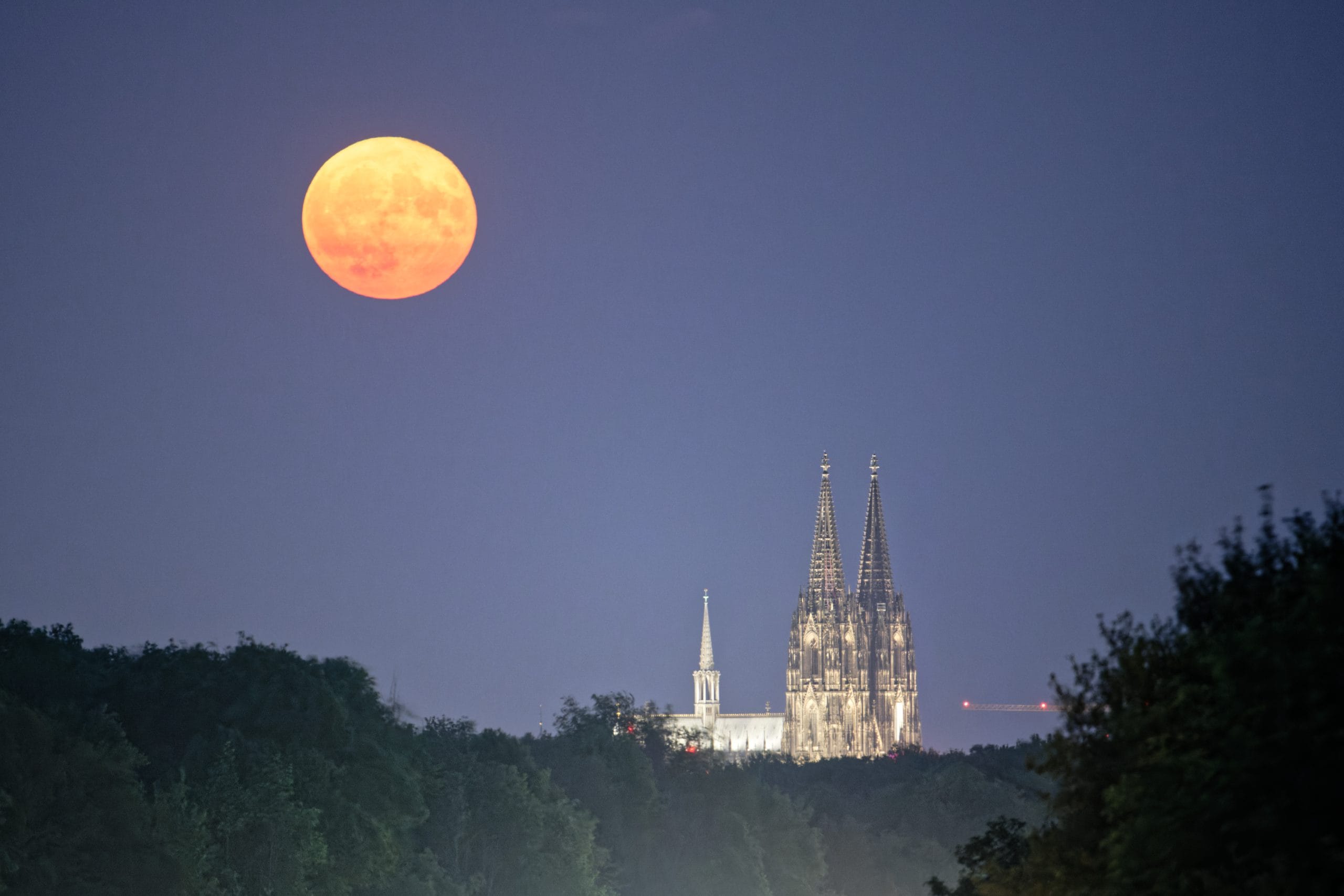 Der Vollmond geht über dem Kölner Dom auf. 