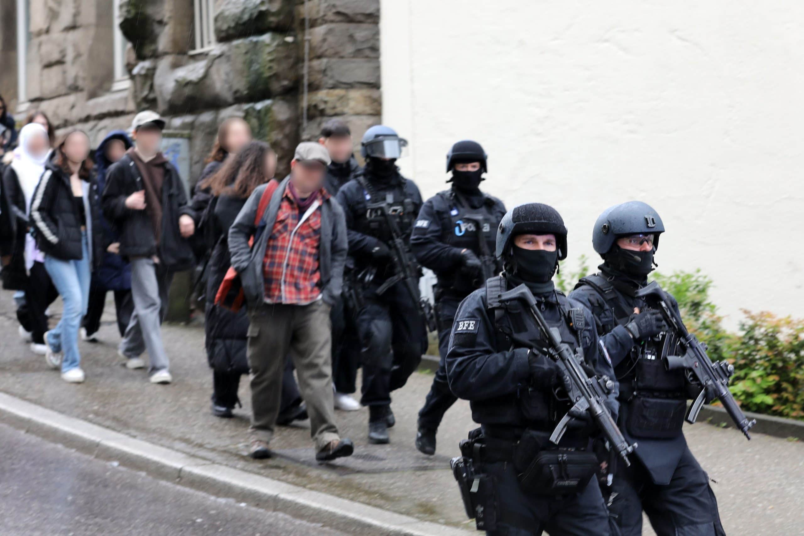 Polizisten führen Schüler aus dem Gebäude in einen Evakuierungsbus. Die Polizei war am Freitag nach einem Hinweis auf eine 